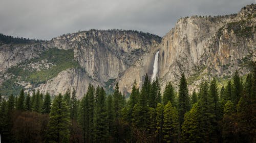 White Waterfalls Between Rocky Mountain during Cloudy Day