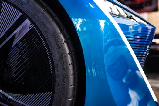 Detail shot of a stylish blue sports car focusing on tire and wheel design with reflective bodywork.