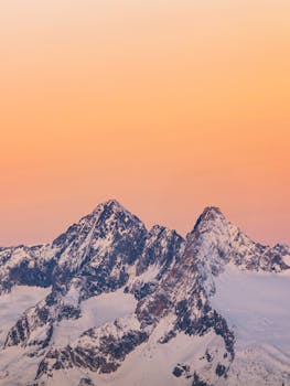 Stunning view of the snow-covered Alps at sunset in Lombardy, Italy, showcasing dramatic skies and winter beauty.