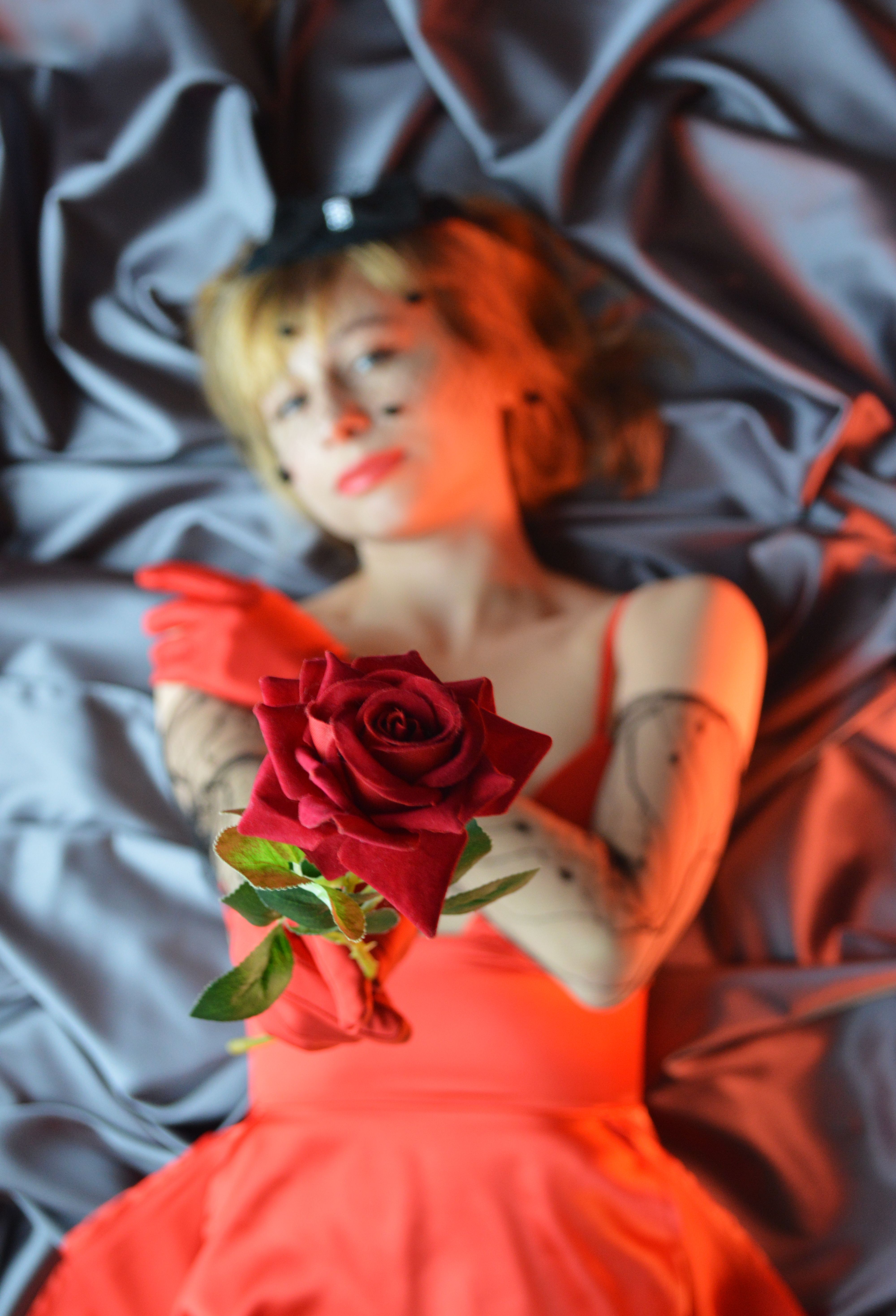 Gentle woman showing blooming rose on crumpled cloth · Free Stock Photo