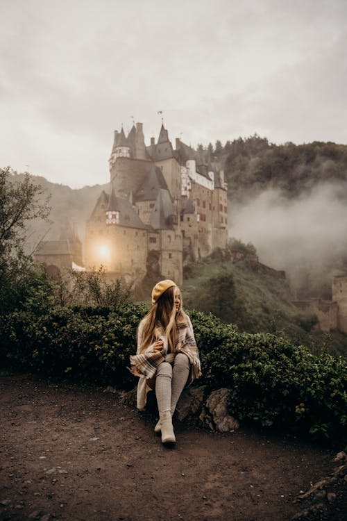 A Woman Sitting on Chopped Wood with Eltz Castle View