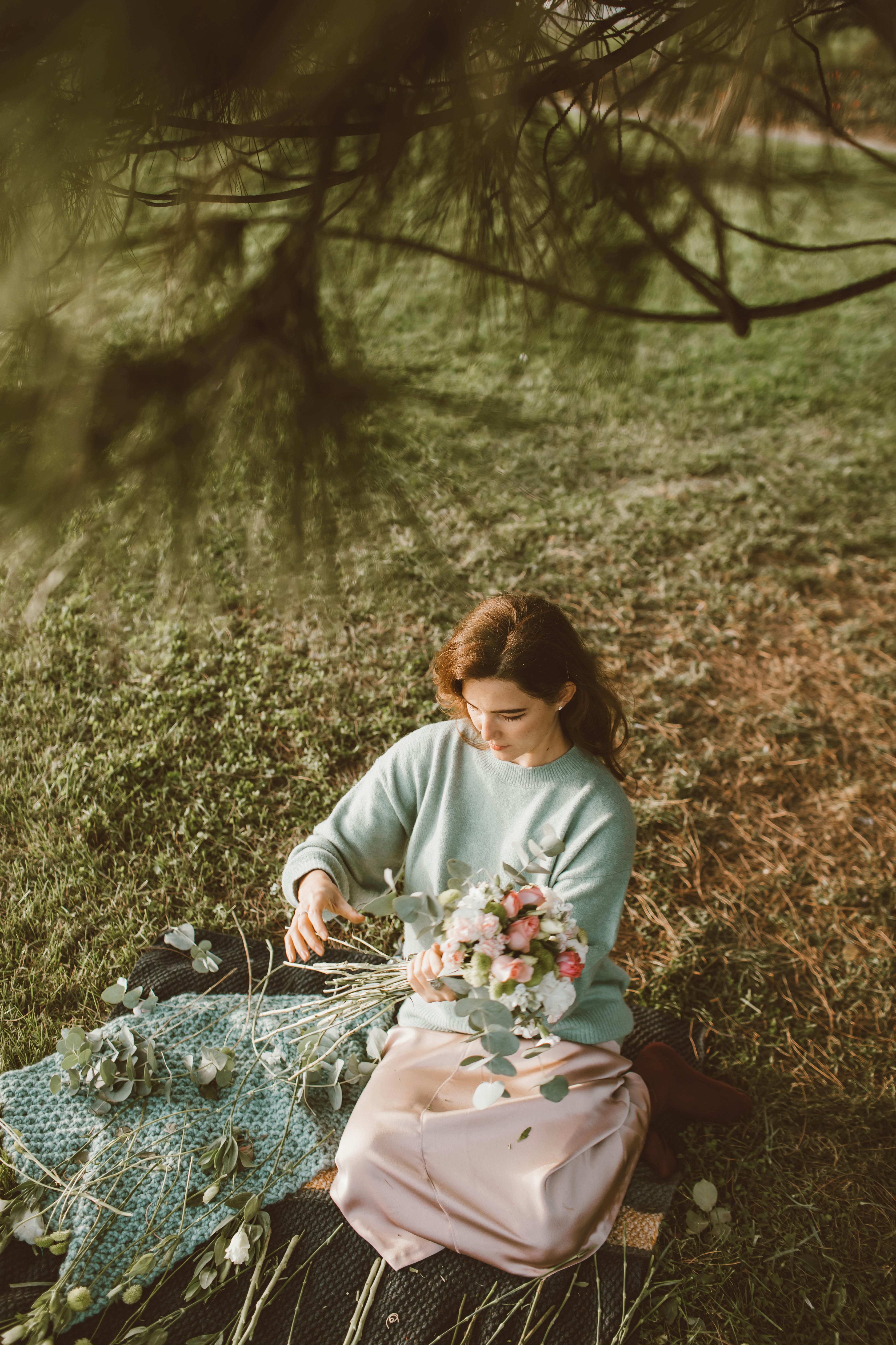 A woman in a serene garden setting arranging a beautiful bouquet of flowers with gentle pastel colors.
