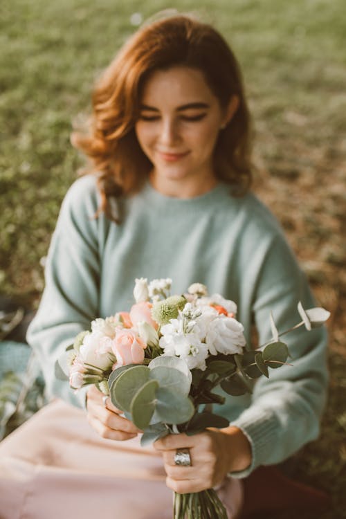 Free Woman in Sweater Holding Flowers Stock Photo