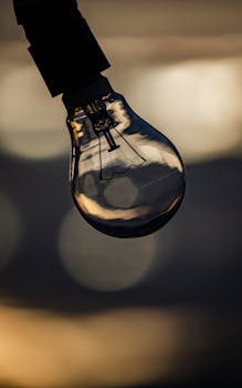 Artistic close-up of a lightbulb with soft reflections and a moody bokeh background.