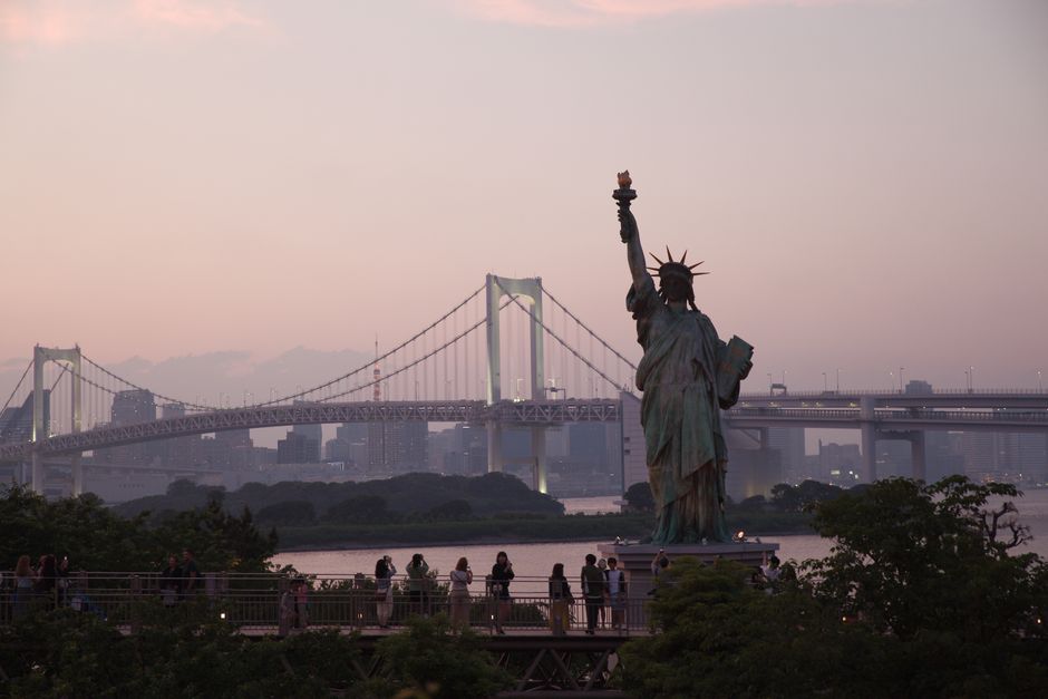 Statue of Liberty replica and Rainbow Bridge at dusk in Tokyo, a stunning cityscape view.