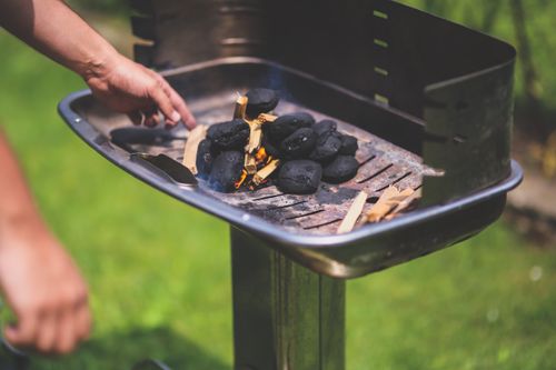 Free Hand preparing charcoal briquettes for grilling outdoors in summer. Stock Photo
