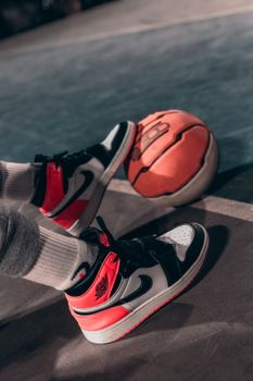 Detailed view of sneakers and a basketball on an outdoor court at night