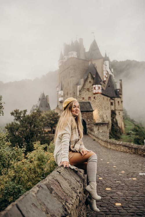 Free Woman Sitting on a Wall Near Eltz Castle while Looking Afar Stock Photo