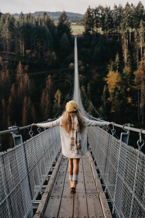 Foto gratuita di una donna che cammina su un ponte sospeso