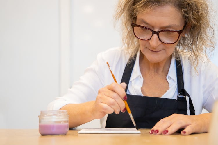 A Woman Painting A Ceramic Tile