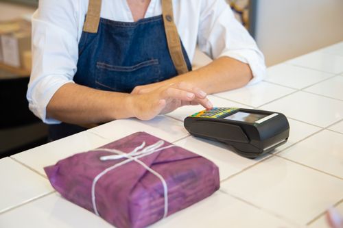 Free A person using contactless payment at a retail counter in Portugal wearing an apron. Stock Photo