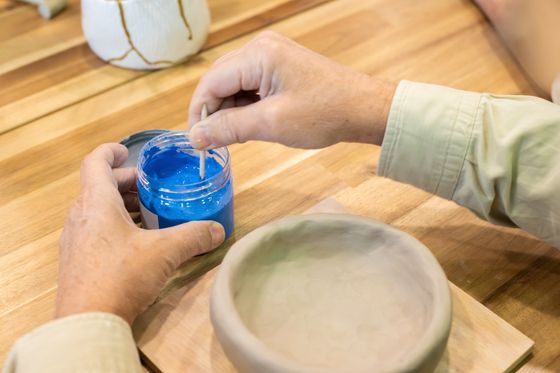 Artisan mixing blue glaze in a studio, photo by Kampus Production on Pexels