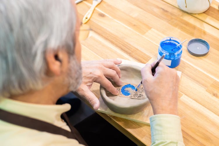 A Man Painting A Ceramic Bowl