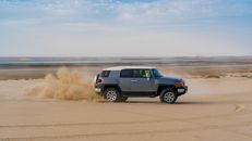 SUV car drifting on sandy beach in sunlight