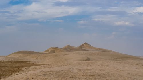 Free Picturesque scenery of tall sandy dunes under cloudy blue sky in endless desert on sunny day Stock Photo