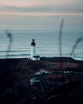 Picturesque view of lighthouse located near calm blue endless water under gray sky in daytime