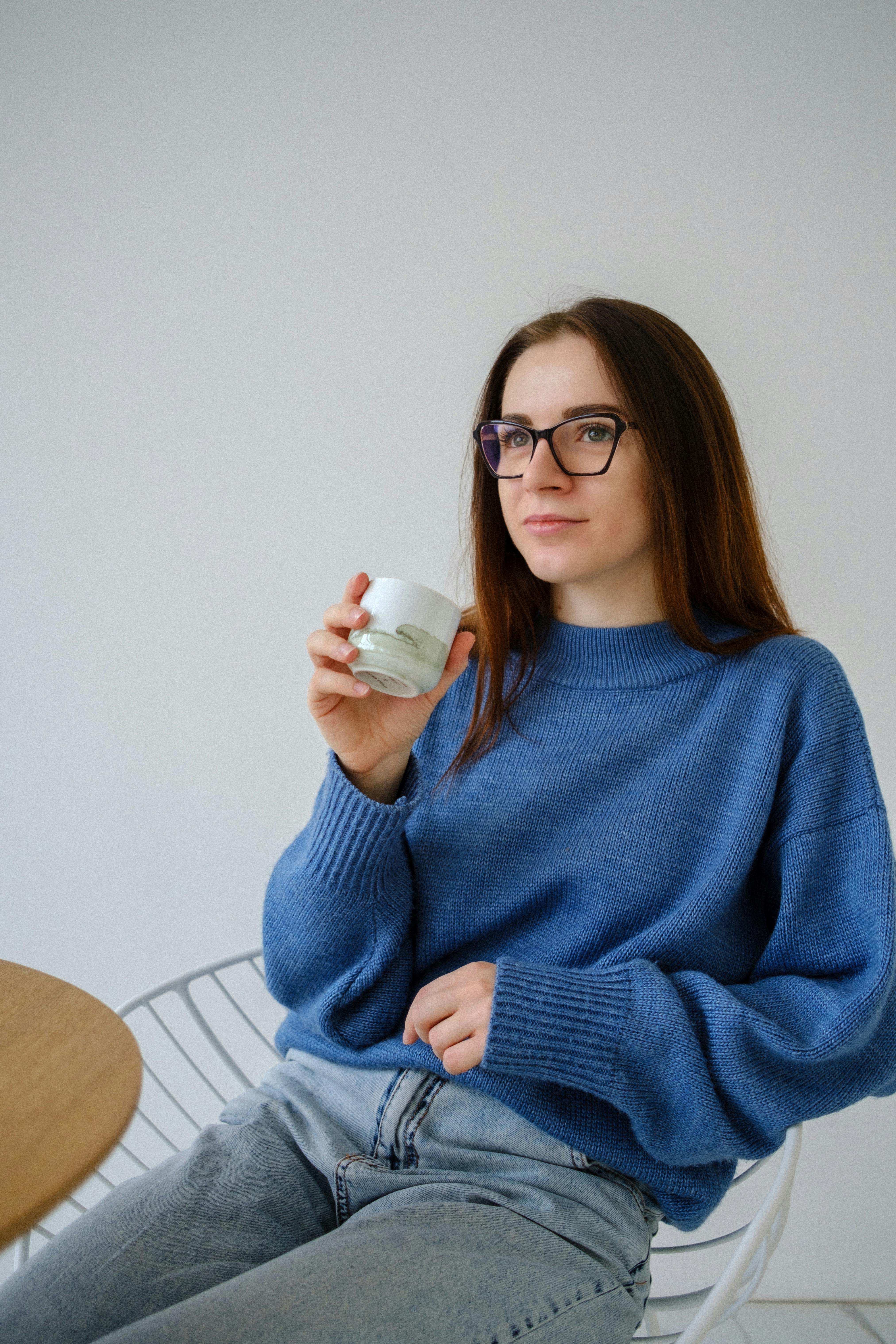 contemplative woman with hot drink on light background