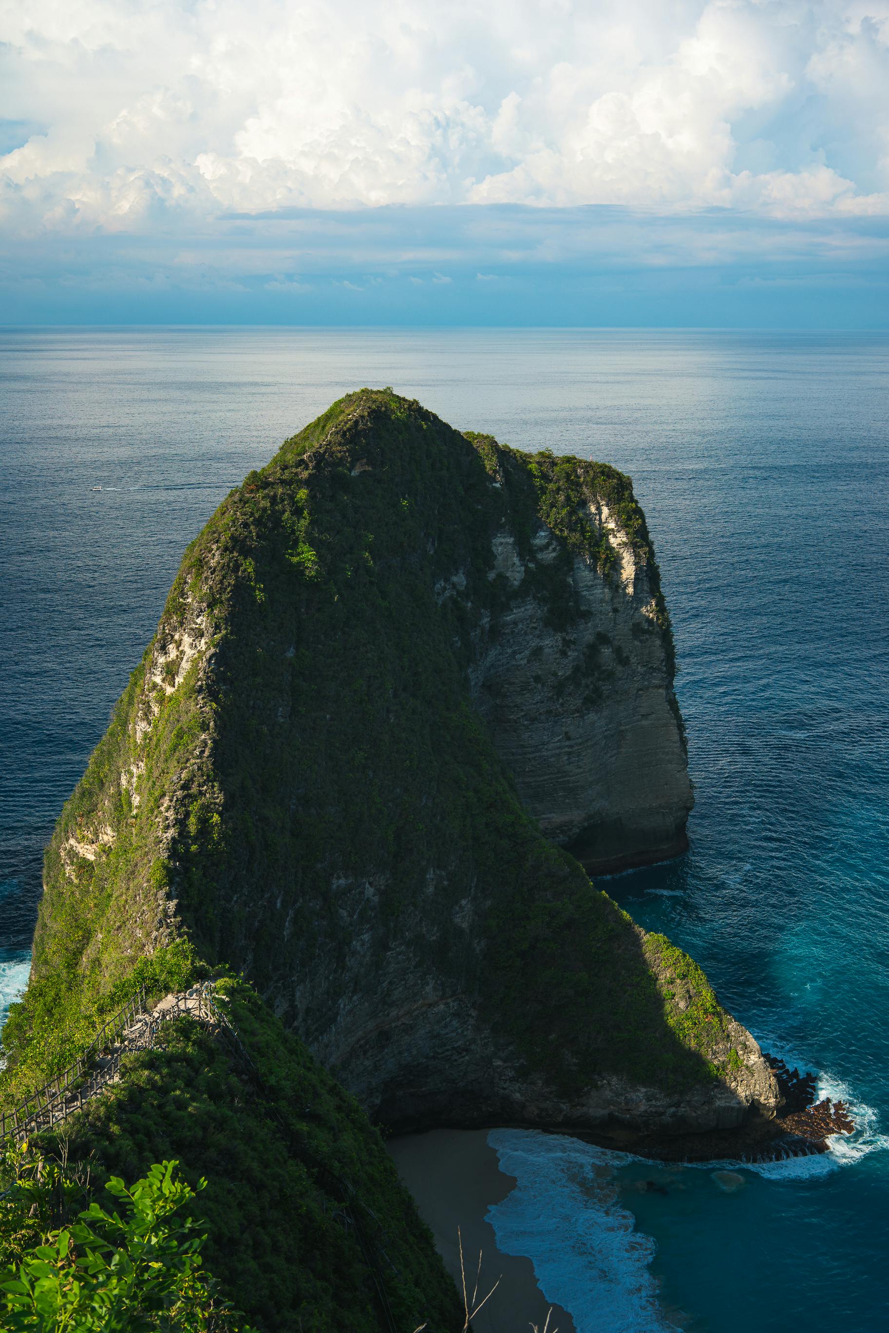 green grass field rock formation beside blue sea