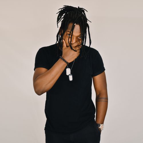 Free Portrait of a man with dreadlocks wearing black in a studio setting. Unique style and casual pose. Stock Photo