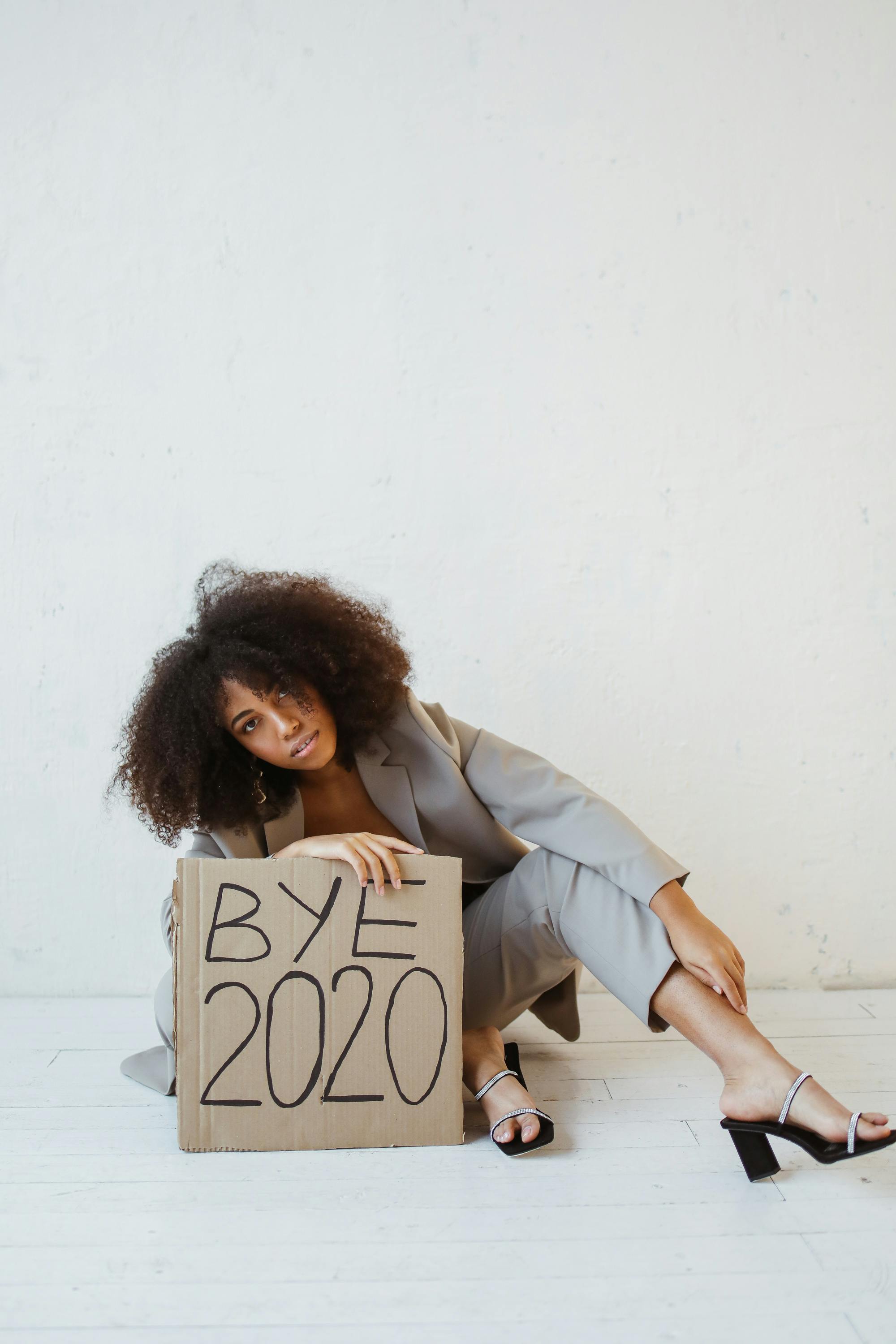 a woman sitting on the floor holding a sign