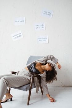 A woman in a chair, surrounded by signs, depicts exhaustion and burnout from 2020.