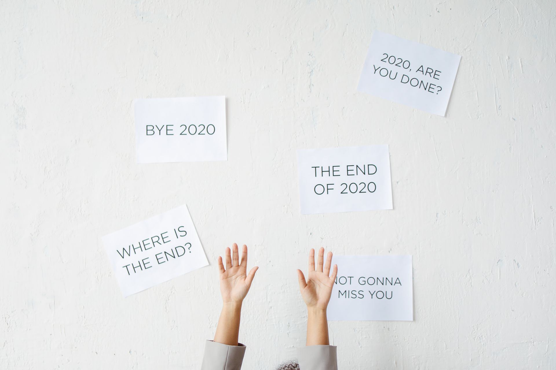 Hands reach up towards motivational text on a wall, saying goodbye to 2020.