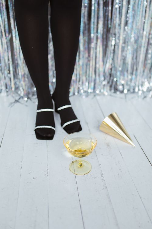 Free Black pantyhose with champagne glass at a festive party setup on a wooden floor. Stock Photo