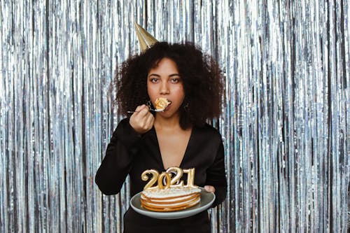 A Woman Celebrating the New Year While Eating a Slice of Cake
