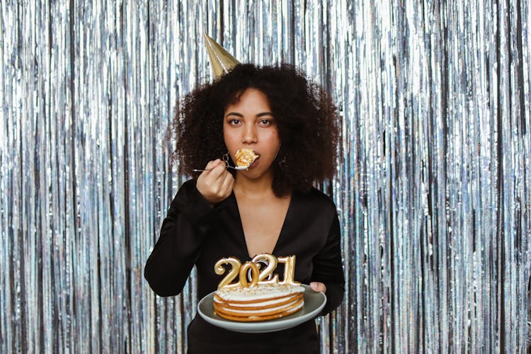 A Woman Celebrating The New Year While Eating A Slice Of Cake