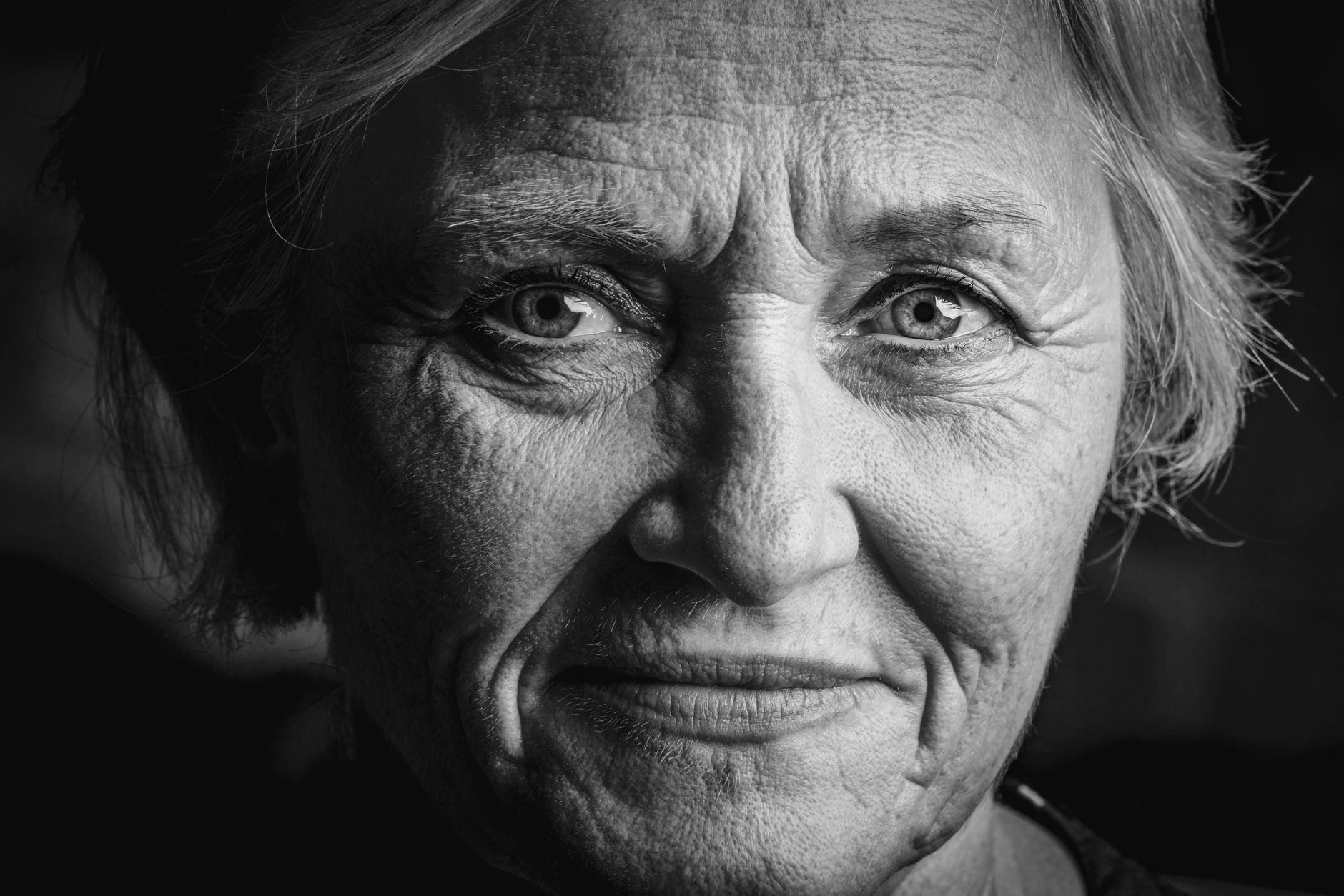 Black and white of crop confident elderly female with short gray hair looking at camera