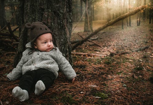 Baby Wearing a Beanie Sitting Under a Tree