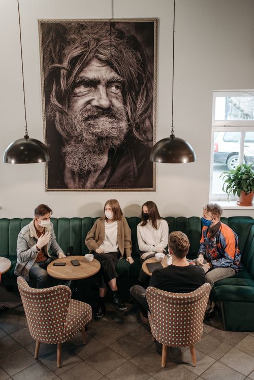 Free A group of friends in a café, engaging in conversation while wearing face masks for protection. Stock Photo