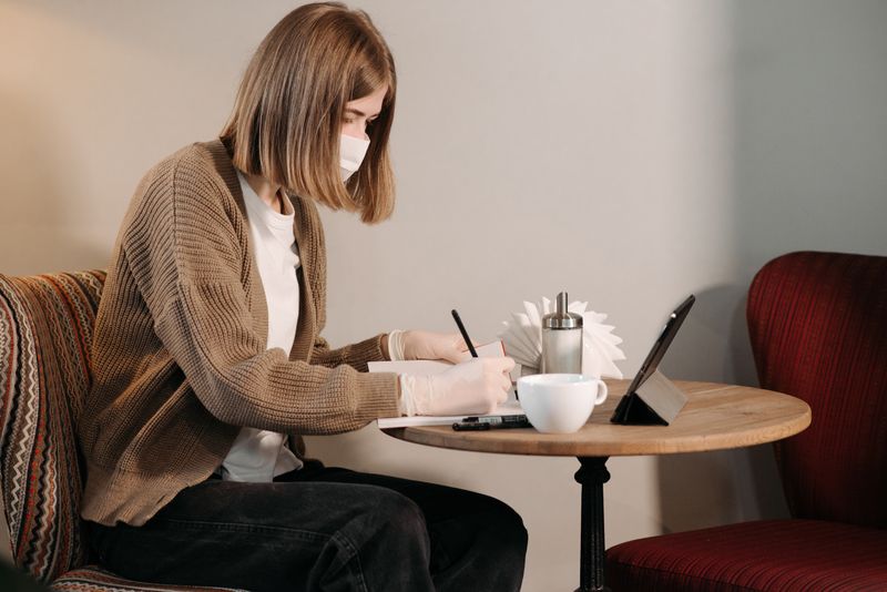 Woman writing in a notebook over coffee