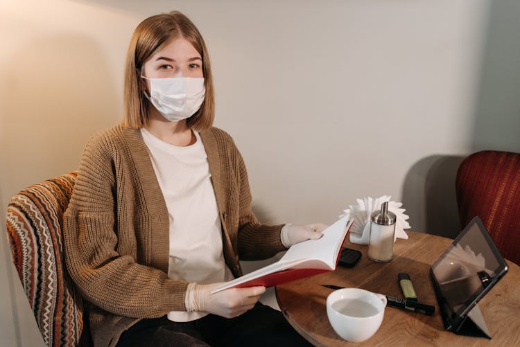 Woman Wearing Facemask Holding Red Notebook