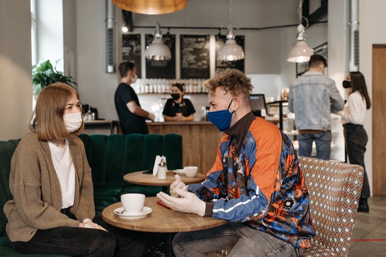 People Wearing Face Masks Having Conversation At The Café