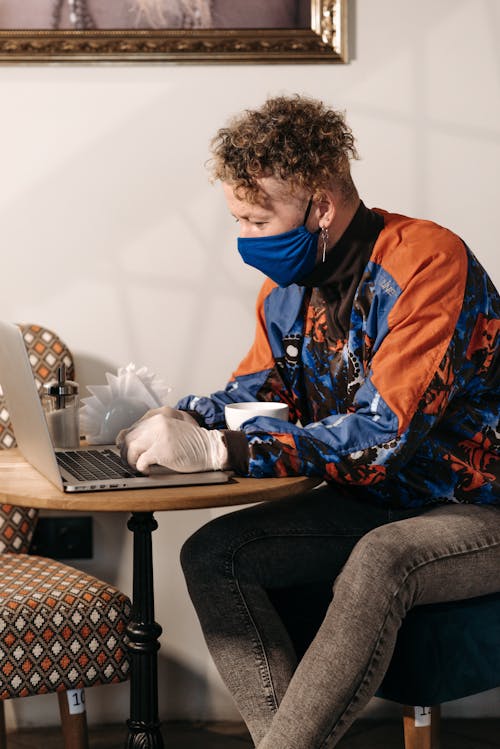 Free Person Wearing Gloves Using a Silver Laptop Stock Photo