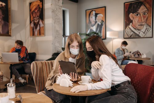 Women Wearing Face Masks Looking at the Screen of a Tablet