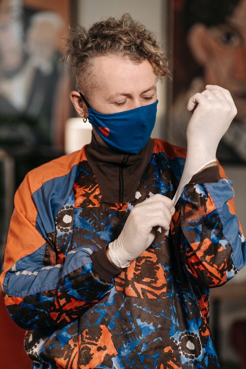 Free Man wearing a colorful jacket, face mask, and latex gloves for personal protection indoors. Stock Photo