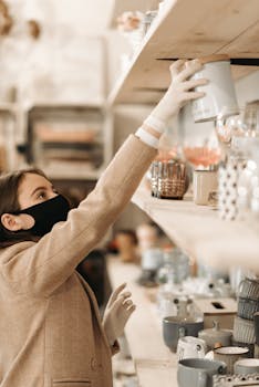 Woman wearing a mask and gloves shops in a boutique, practicing safety.