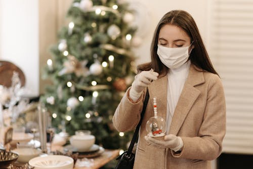 Free Woman Wearing White Face Mask Holding a Christmas Ornament Stock Photo