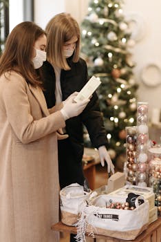Two women wearing face masks shop for Christmas decorations indoors, highlighting new normal during pandemic.