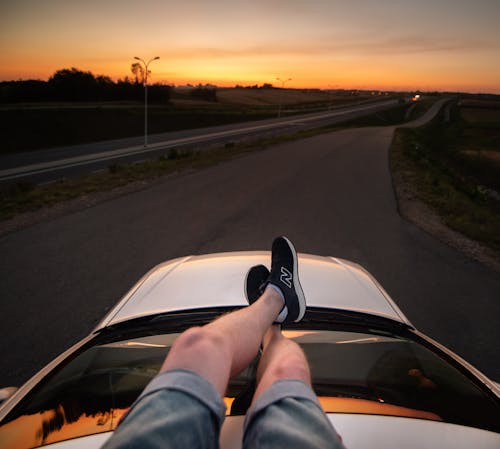 Free Unrecognizable man sitting on car roof Stock Photo