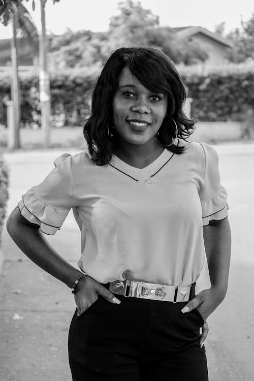 Free Black and white of young content ethnic female with toothy smile looking at camera on pavement Stock Photo