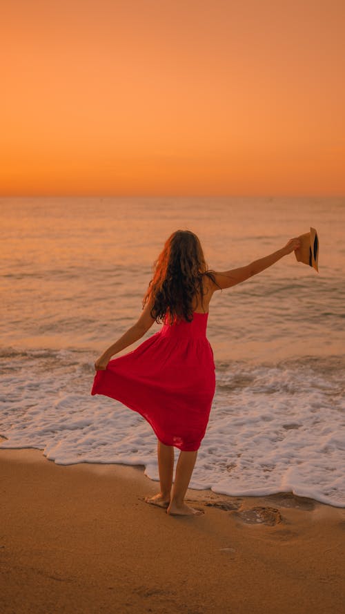 Free Unrecognizable woman standing on seashore at sunset Stock Photo