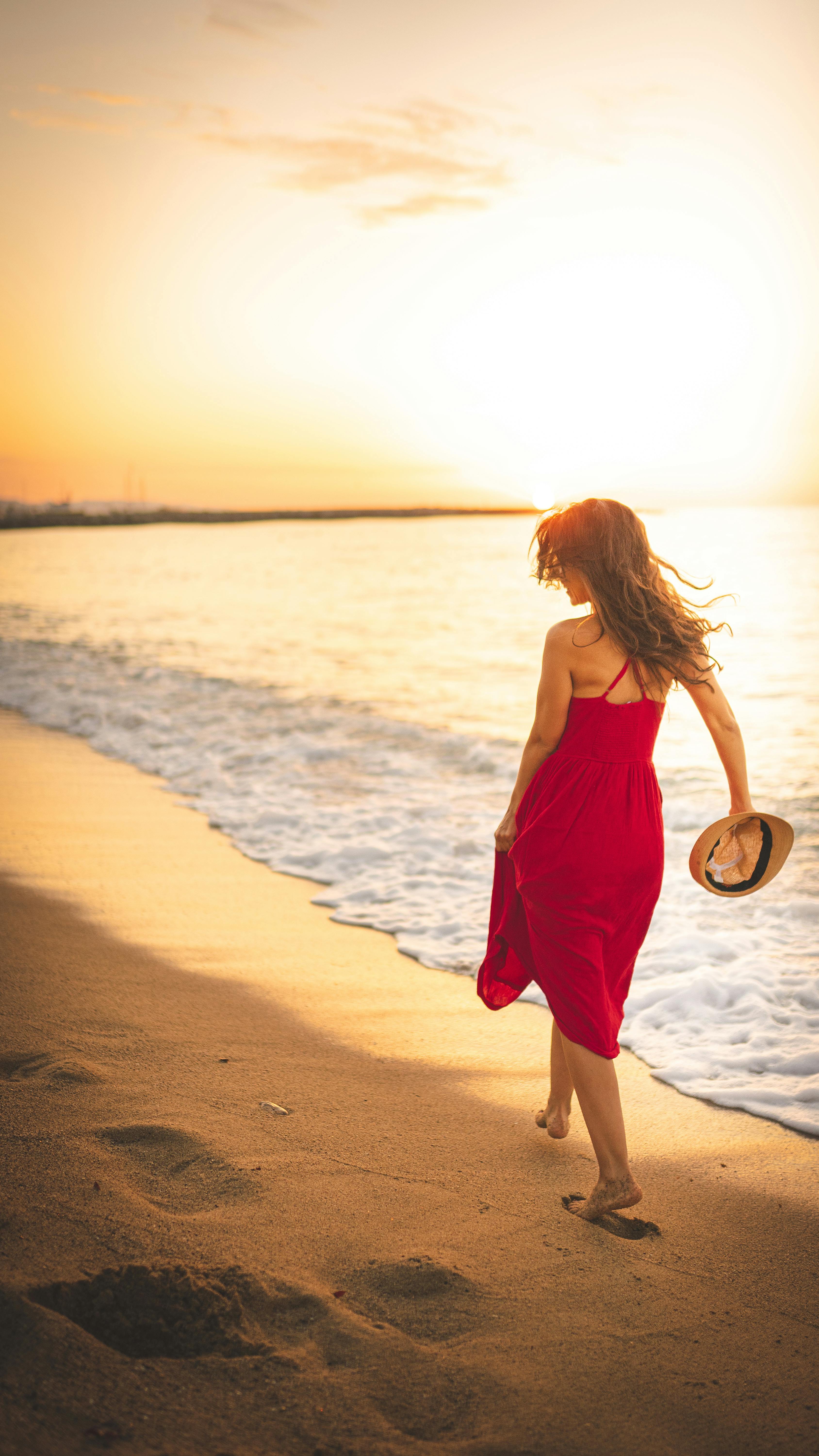 Anonymous woman walking on sandy beach · Free Stock Photo