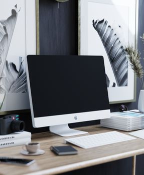 A stylish home office setup featuring a computer, camera, and decorative elements on a wooden desk.
