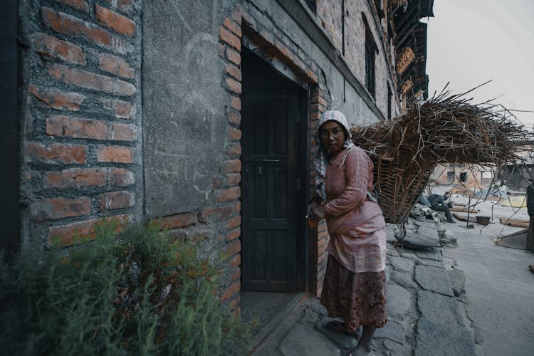 Black Woman Carrying Twigs In Basket On Urban Street