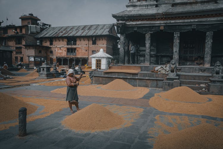 Unrecognizable Ethnic Woman Near Piles Of Rice On Urban Square