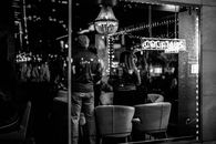 Black and white of young anonymous people spending time in bar with bright lights at night
