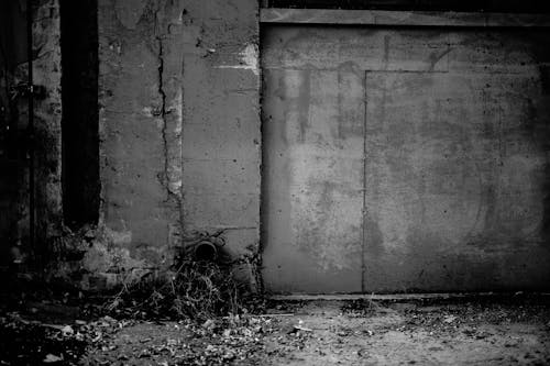 Black and white of aged weathered wall with cracked stucco of forgotten gloomy building